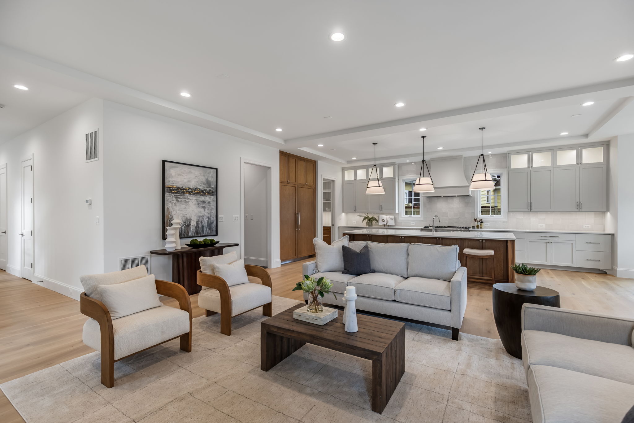 A bright, open-concept living room featuring clean architectural lines, premium custom cabinets, and large windows that flood the space with natural light.